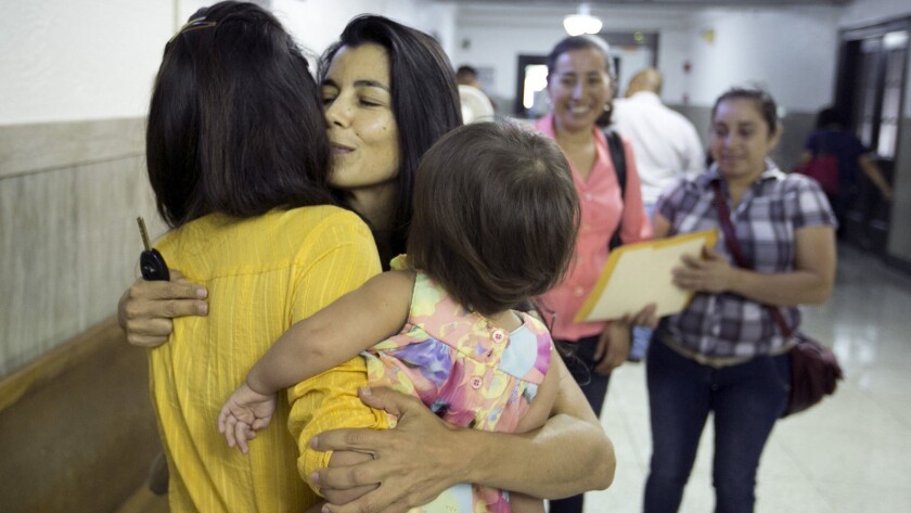 An attorney, center, hugs a mother and daughter after filing a petition at a Texas courthouse in July 201on the mother's behalf for special juvenile immigrant status.
