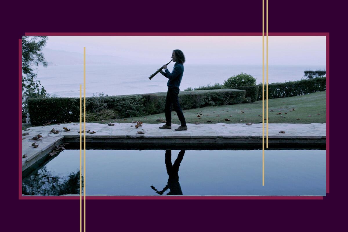 A man walks next to a pool while playing an instrument.