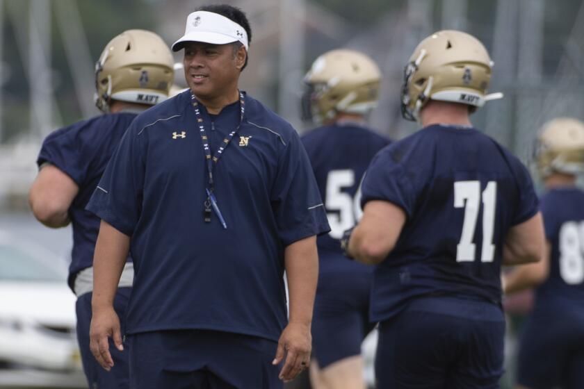 Navy head coach Ken Niumatalolo stands on the field as players warm up for works out during NCAA college football training camp, Friday, Aug. 2, 2019, in Annapolis, Md. (AP Photo/Tommy Gilligan)