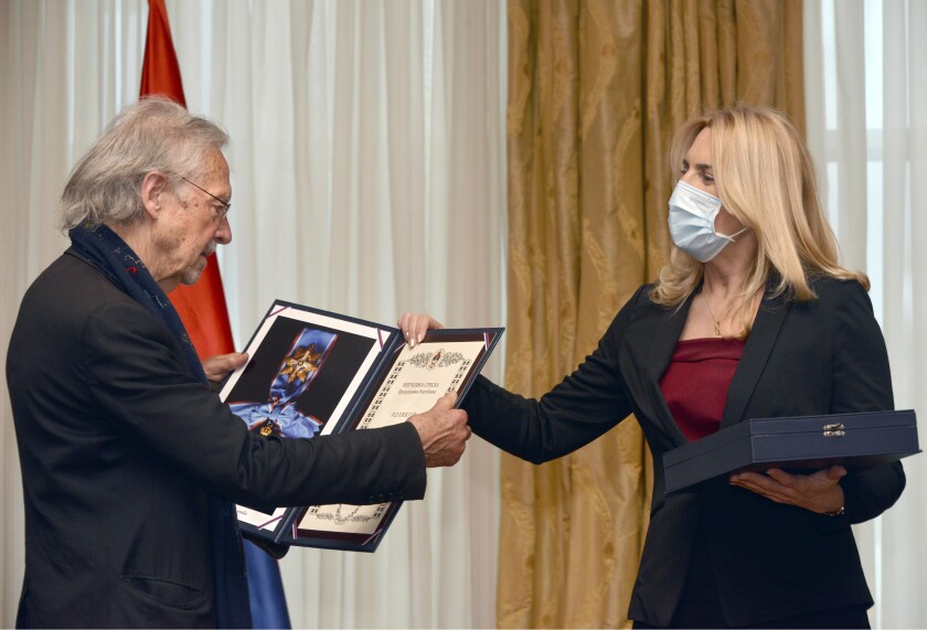 Austrian author Peter Handke, left, receives the Order of the Republika Srpska from President of Republika Srpska Zeljka Cvijanovic during the ceremony in Banja Luka, Bosnia, Friday, May 7, 2021. The 2019 Nobel Literature Prize laureate Peter Handke was on Friday awarded top honors from Bosnian Serbs, building on the controversy stemming from his apologist views over Serb war crimes during the 1990s' wars in the Balkans. (AP Photo/Radivoje Pavicic)