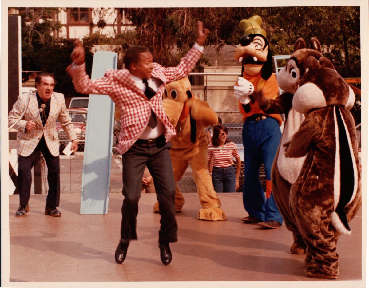 A man jumps near Disney characters.