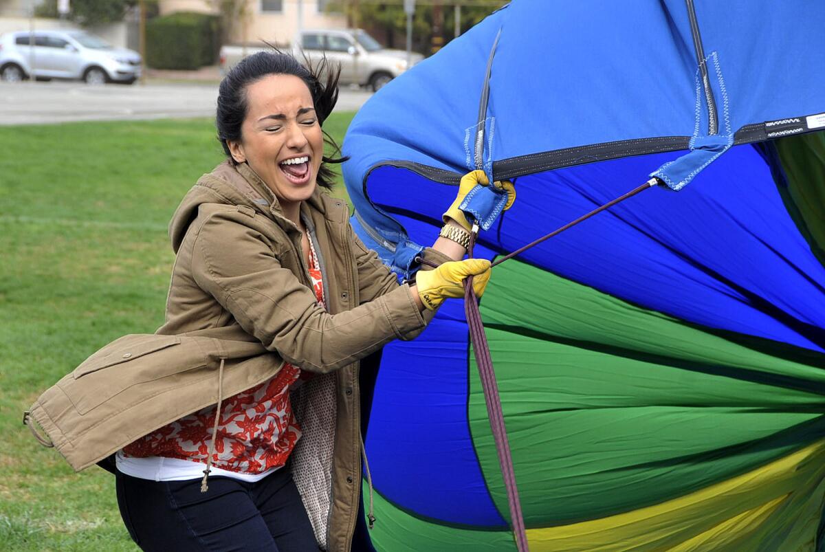 6th grade math and science teacher Catherine Eskandar is caught in a fan blast of air that was used to inflate a hot air balloon that she and fellow 6th grade teacher Sarah Reed float in above about 300 6th grade students at Jordan Middle School in Burbank on Monday, October 28, 2013. The balloon, with a capacity equal to 77,000 basketballs, was provided by Details Above All Hot Air Balloons to give 6th graders a live demonstration of a balloon in flight.