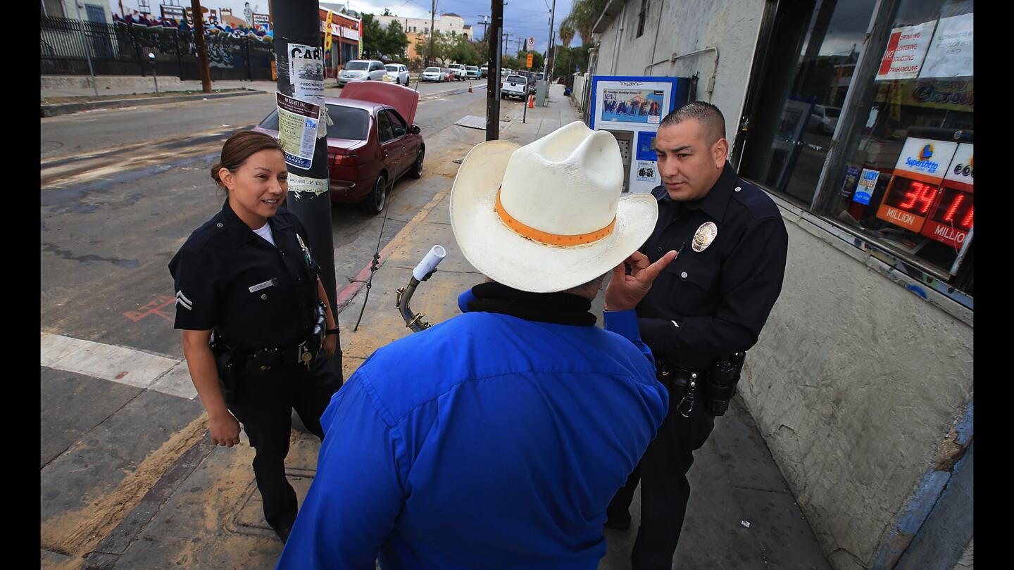 LAPD officers Norma Perez, left, and Eric Perez talk with a mariachi musician while walking a foot beat along Cesar E. Chavez Avenue in Boyle Heights on May 14, 2015. The veteran officers were hand-picked for the assignment, which is an effort by the LAPD to establish relation-based policing practices in the city.