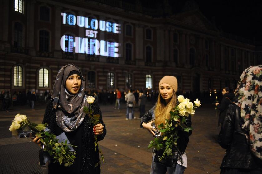 Women give out white roses in Toulouse, southern France, during a gathering to pay tribute to the victims of the deadly attack in Paris on the staff of the satirical weekly Charlie Hebdo.