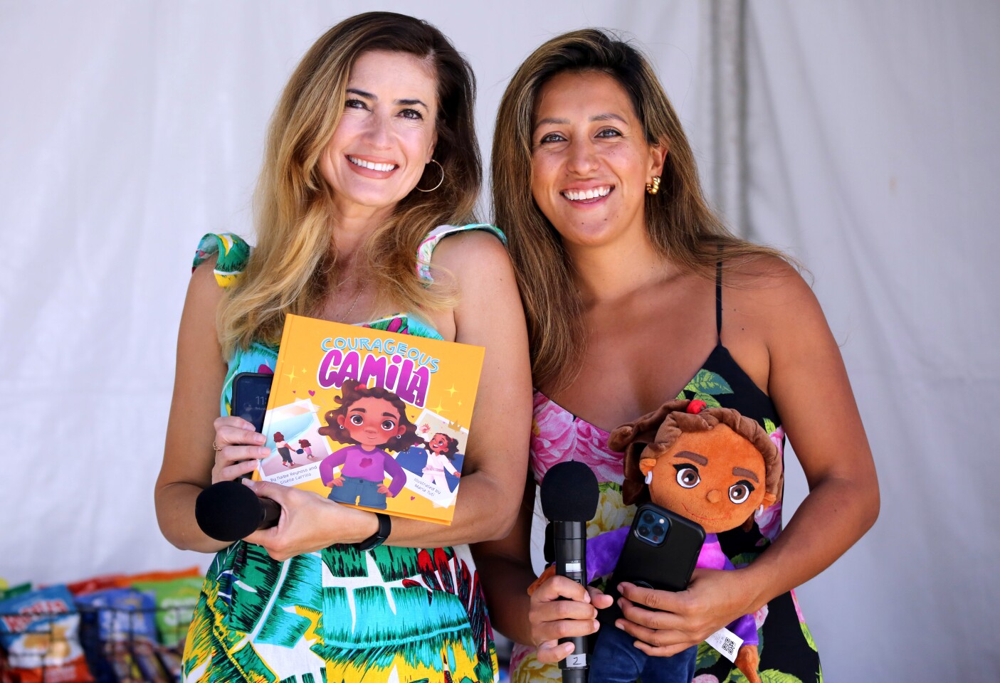 Authors Naibe Reynoso, left, and Giselle Carrillo, right, show their collaborative book called Courageous Camilla at the L.A. Times Festival of Books' Los Angeles Times en Espanol area at the University of Southern California in Los Angeles on Saturday, April 23, 2022.