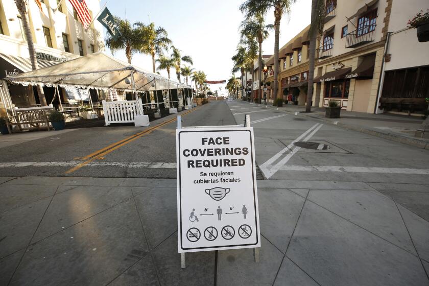 VENTURA, CA - DECEMBER 17: Signs remind visitors on South California Street at East Main Street in downtown Ventura to take precautions as Health officials in Ventura County say parties, indoor church services and youth sports events currently banned amid COVID-19 restrictions are continuing, hindering the county's ability to fight the spreading coronavirus. The county's intensive care unit capacity has dropped to 1%, and COVID-19 hospitalizations have broken records for 10 consecutive days. On Sunday, 181 COVID-19 patients were in the county's hospitals, 72% higher than the peak of the July surge. Ventura County on Thursday, Dec. 17, 2020 in Ventura, CA. (Al Seib / Los Angeles Times)