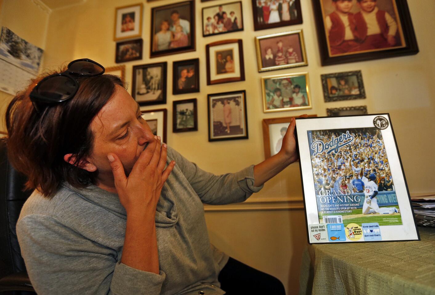 Mandy Pifer, girlfriend of Los Angeles resident Shannon Johnson, who was one of 14 people killed in the San Bernardino shooting rampage on Wednesday, shows a framed LA Dodgers magazine cover with Johnson pictured in the crowd that hangs on a wall of family photos and memorabilia in his apartment.