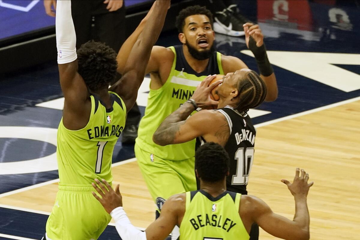 San Antonio Spurs' DeMar DeRozan, center, looks at the basket as Minnesota Timberwolves' Karl-Anthony Towns looms over him in the second half of an NBA basketball game Saturday, Jan. 9, 2021, in Minneapolis. (AP Photo/Jim Mone)
