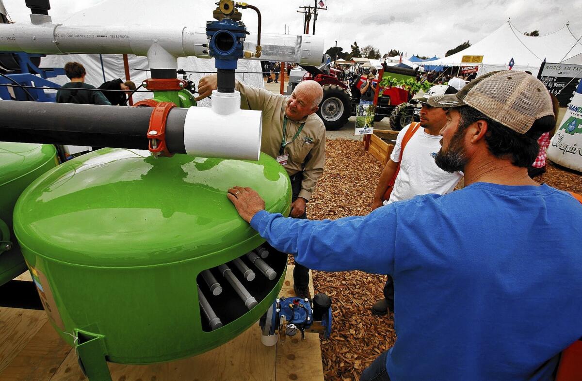 Steve Johnson, left, the manager of national tech services for Jain Irrigation Inc., offers a demonstration to people looking for watering systems at the World Ag Expo, a global agriculture fair, in Tulare, Calif.