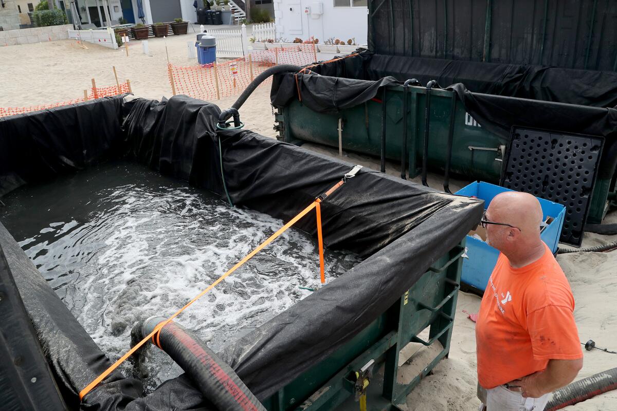 Field manager Robert Mooney watches as sea water is pumped into one of two large construction containers.