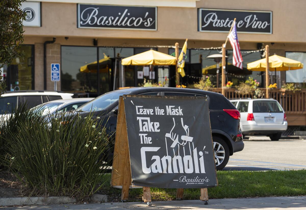 A sign reading "Leave the mask, take the cannoli" sits outside Basilico's in Huntington Beach.