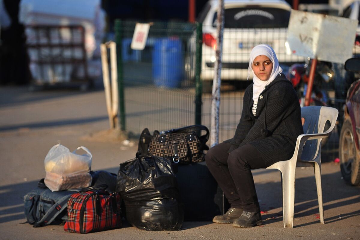 Syrian woman with her belongings at the Syrian-Turkish border near Hatay, Turkey. 