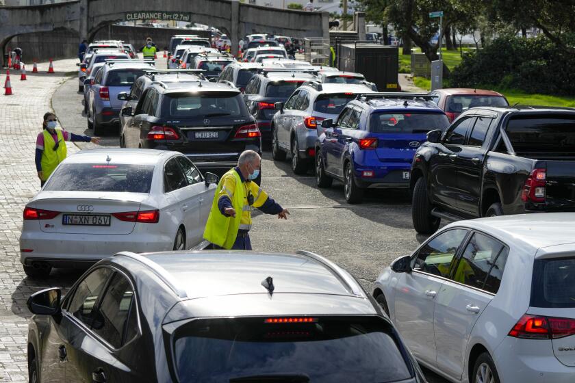 Traffic marshalls direct cars at a drive-through COVID-19 testing clinic at Bondi Beach in Sydney, Australia, on Jan. 8, 2022.