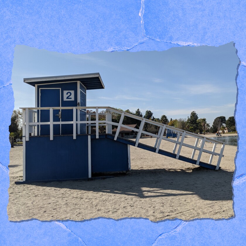 A lifeguard station painted blue with a No. 2 on its side, sitting on a flat, sandy beach.