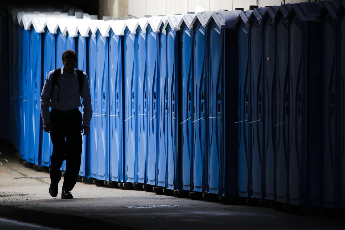 A pedestrian walks past portable toilets staged ahead the World Meeting of Families and Pope Francis's scheduled visit, Tuesday, Sept. 22, 2015, in Philadelphia. (AP Photo/Matt Rourke)