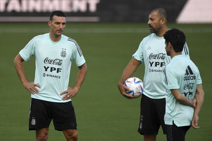 Argentina soccer coach Lionel Scaloni, left, talks to his staff as his players warm up during practice Thursday, Sept. 22, 2022, in Fort Lauderdale, Fla. Argentina is scheduled to play against Honduras on Friday in an international friendly. (AP Photo/Michael Laughlin)