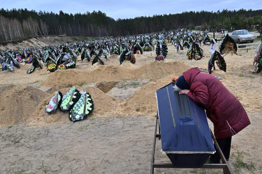 A woman reacts next to the coffin of her husband during a funeral at a cemetery in Irpin on April 19, 2022, where there are at least three rows of new graves for those killed during the Russian invasion of Ukraine. (Photo by Sergei SUPINSKY / AFP) (Photo by SERGEI SUPINSKY/AFP via Getty Images)