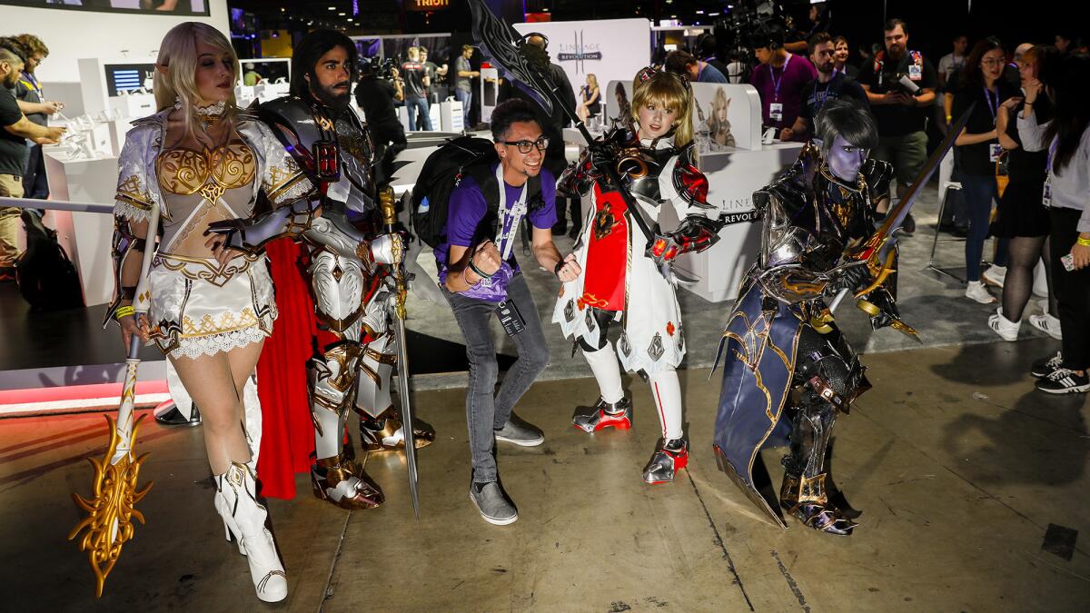 At a past Con, Jeffrey Gates, center, who uses the Twitch handle thekelekter, posed with characters from the video game "Lineage" in the exhibitors hall at TwitchCon.