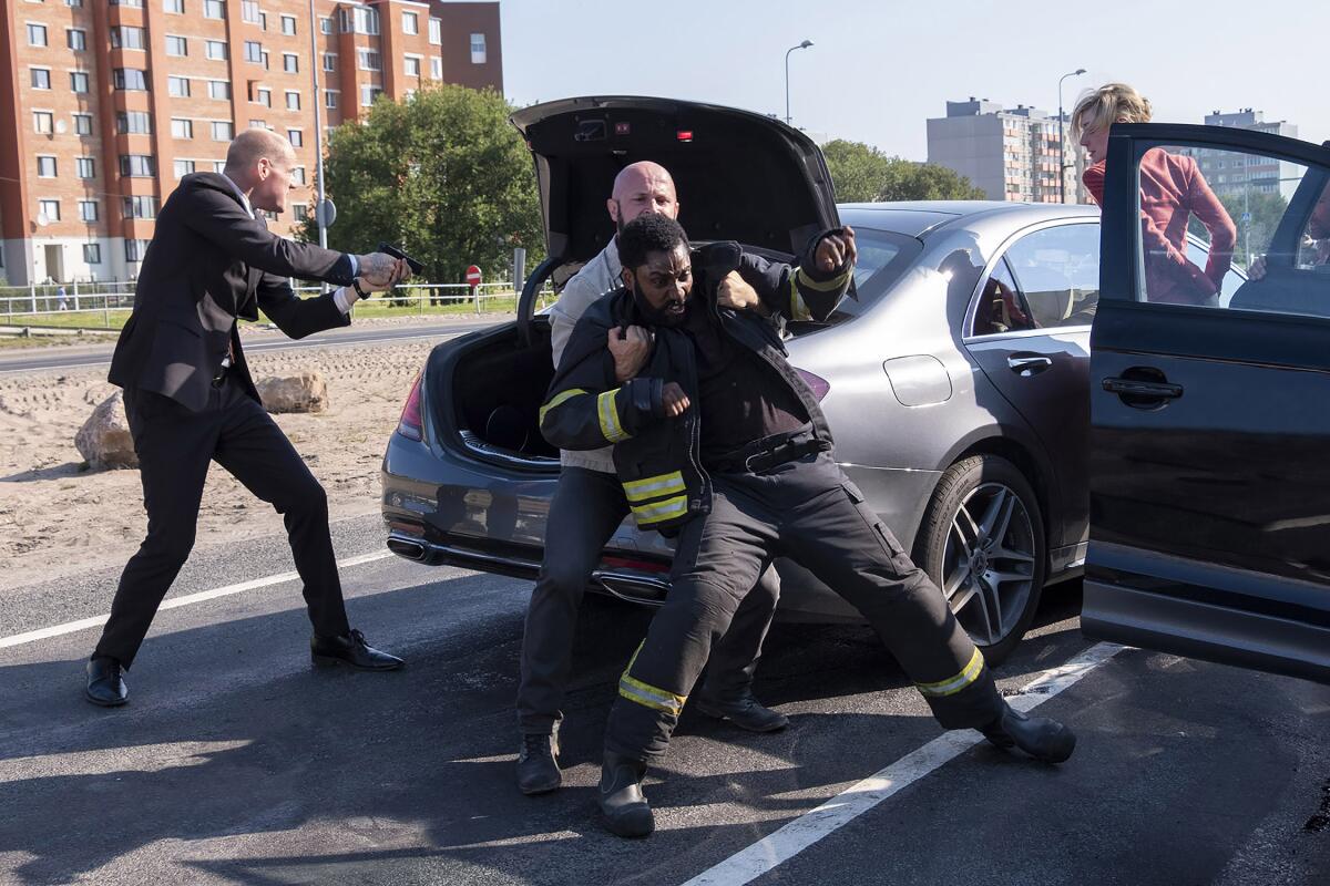 Actors stage a fight next to a car 