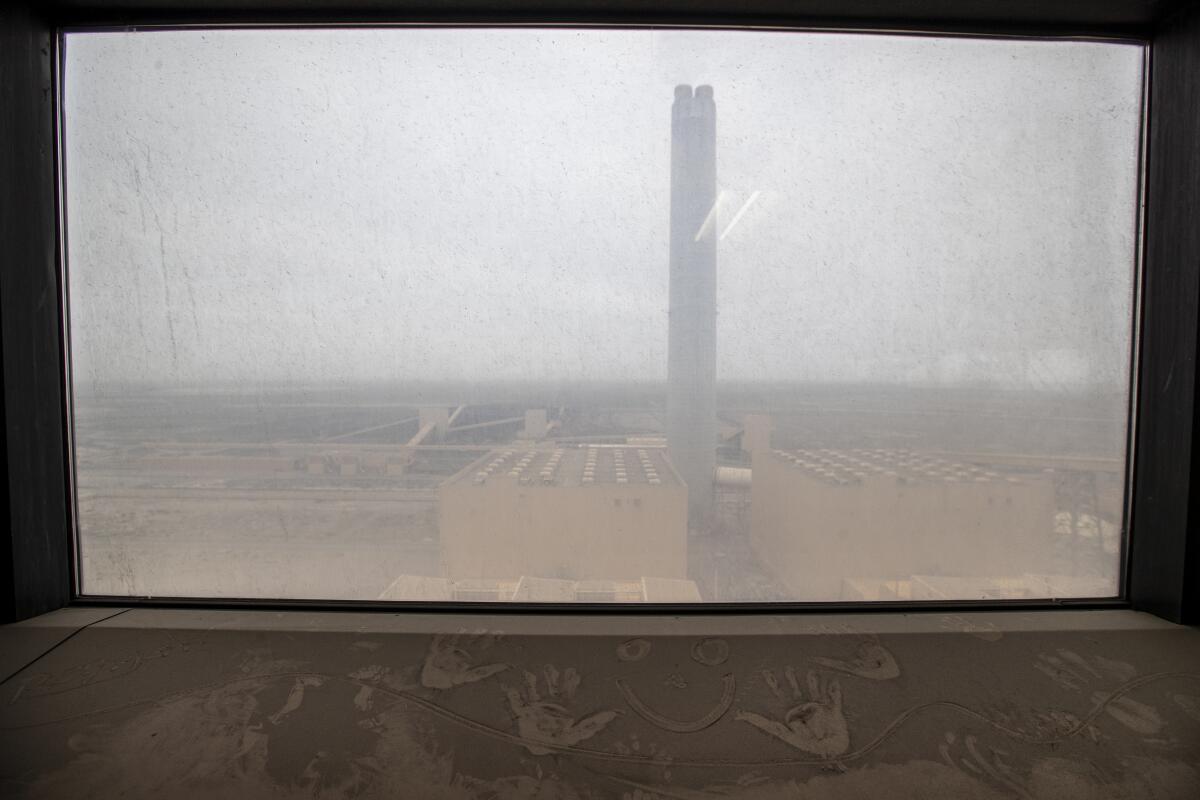 A cloudy window looks onto a power plant.