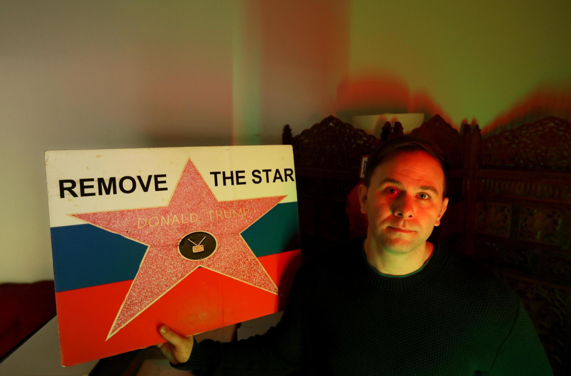 Andrew Rudick holds up a sign he created to "remove the star" of former President Trump from the Hollywood Walk of Fame.