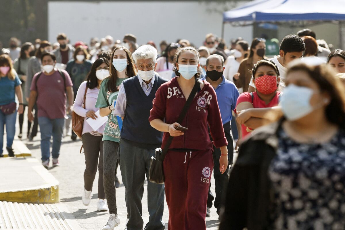 Masked people stand in a line in Mexico City.