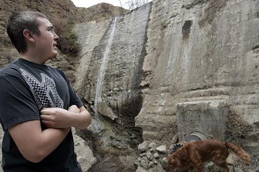 Steven Hand casts a wary eye toward a dam that's 100 yards from his father's house in Orange County's Modjeska Canyon. The family stayed during the October wildfires, and they refuse to evacuate now.