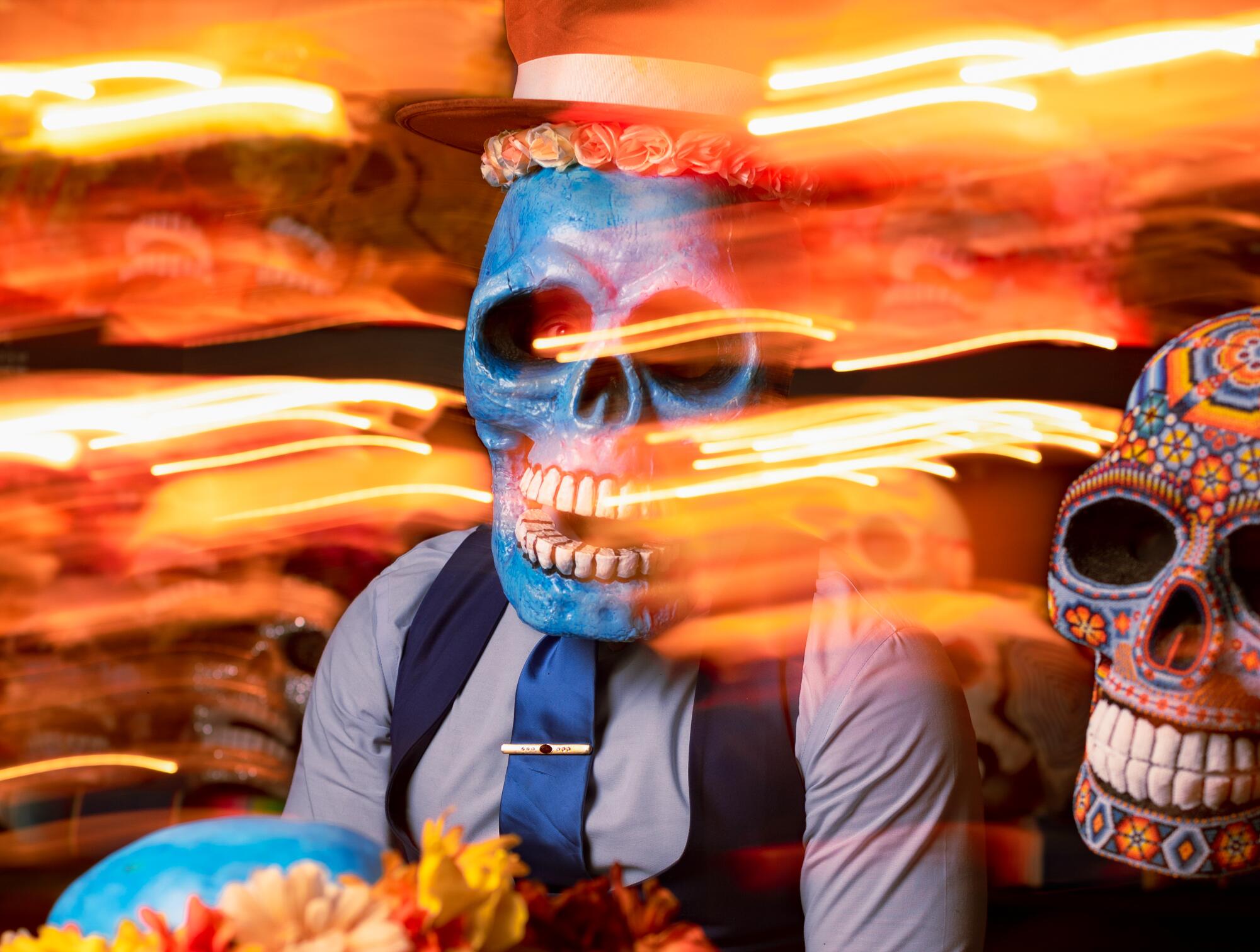 Butch Locsin wearing a blue skull mask, with glowing orange lights streaked around him.