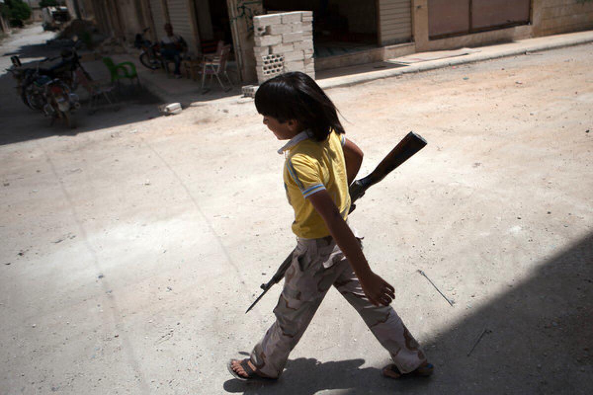 A Syrian boy carries an old rifle to rebel fighters in the the town of Maaret al-Numan.