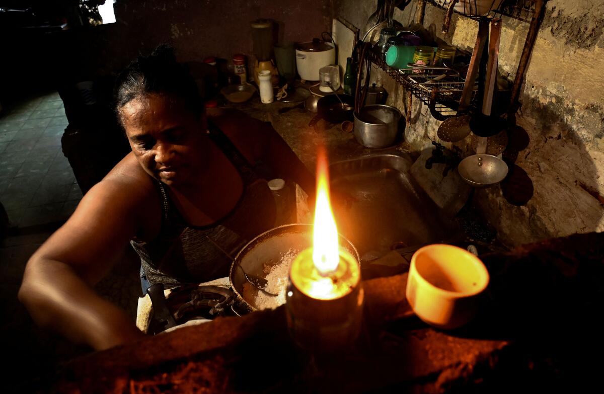 A woman cooks indoors by candlelight