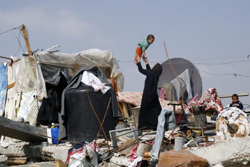 A Palestinian woman plays with her child on the rubble of their family's home, which was destroyed during the 50-day war between Israel and Hamas in the Gaza Strip.