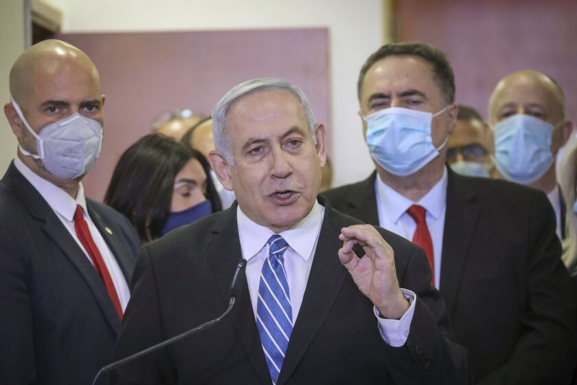 File - In this Sunday, May 24, 2020 file photo, Israeli Prime Minister Benjamin Netanyahu, accompanied by members of his Likud Party in masks, delivers a statement before entering the district court in Jerusalem. Netanyahu is on trial for accepting gifts from wealthy friends. But that has not stopped him from seeking another gift from a wealthy friend to pay for his multi-million-dollar legal defense. The awkward arrangement opens a window into the very ties with billionaire friends that plunged Netanyahu into legal trouble and sheds light on the intersection of money and Israeli politics. (AP Photo/Yonatan Sindel/Pool Photo via AP, File)