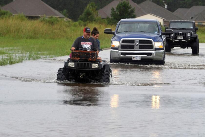 Jason Hendry drives his daughter, Callie, out of Westwood Heights on his ATV in Lumberton, Texas, on Sunday, Aug. 27, 2017. The remnants of Hurricane Harvey sent devastating floods pouring into Houston Sunday as rising water chased thousands of people to rooftops or higher ground. (Ryan Pelham/The Beaumont Enterprise via AP)