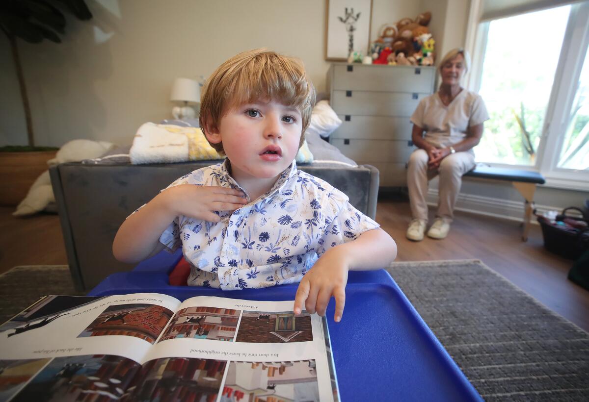 Andrew West, 7, reads a picture book with home nurse Peggy Koustik in his Newport Beach home.