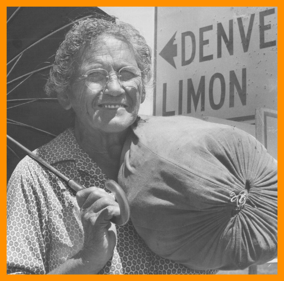 black and white photo of a woman holding a sack and an umbrella