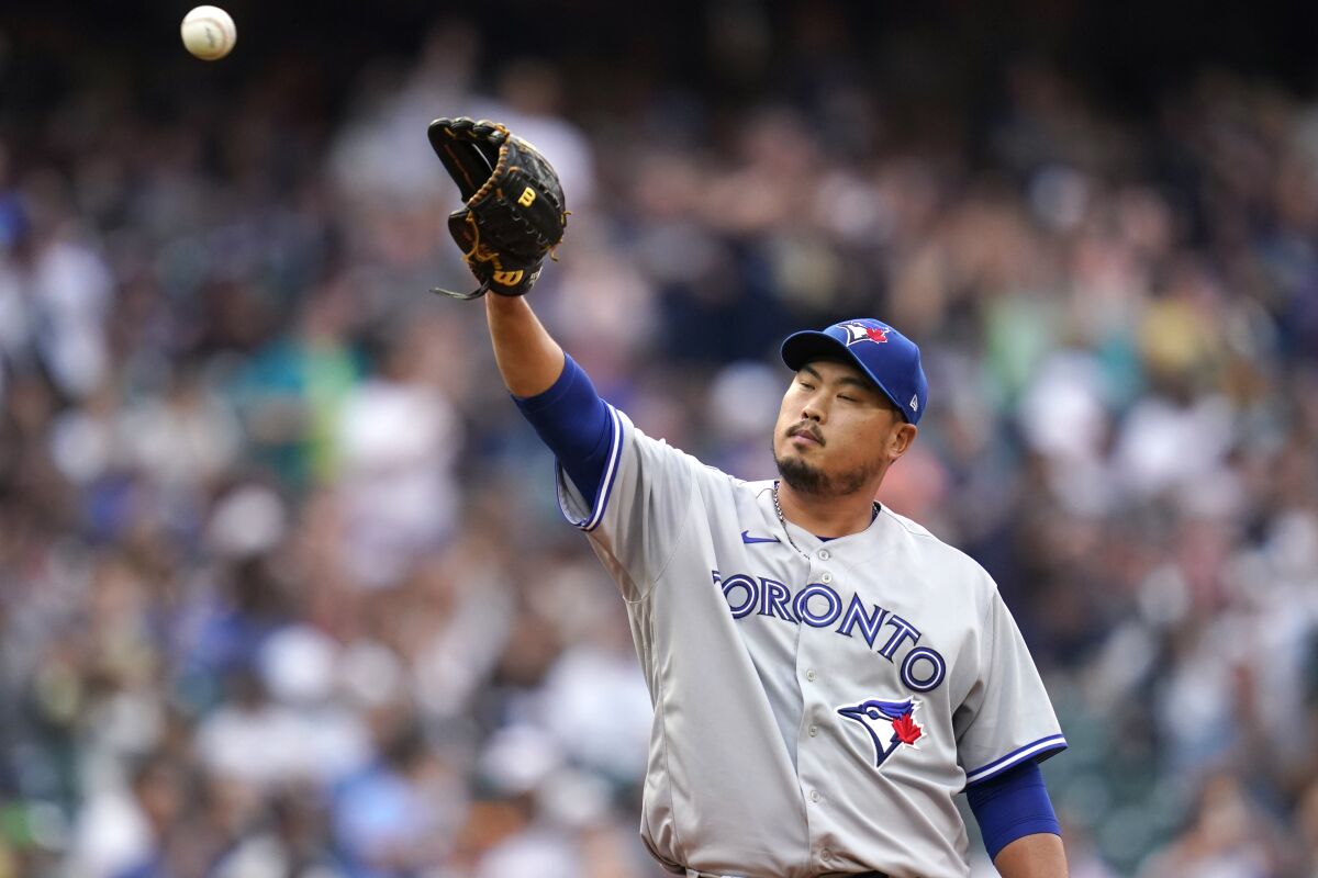 Toronto Blue Jays starting pitcher Hyun Jin Ryu reaches for a new ball after giving up a two-run home run to Seattle Mariners' Ty France during the first inning of a baseball game Saturday, Aug. 14, 2021, in Seattle. (AP Photo/Elaine Thompson)