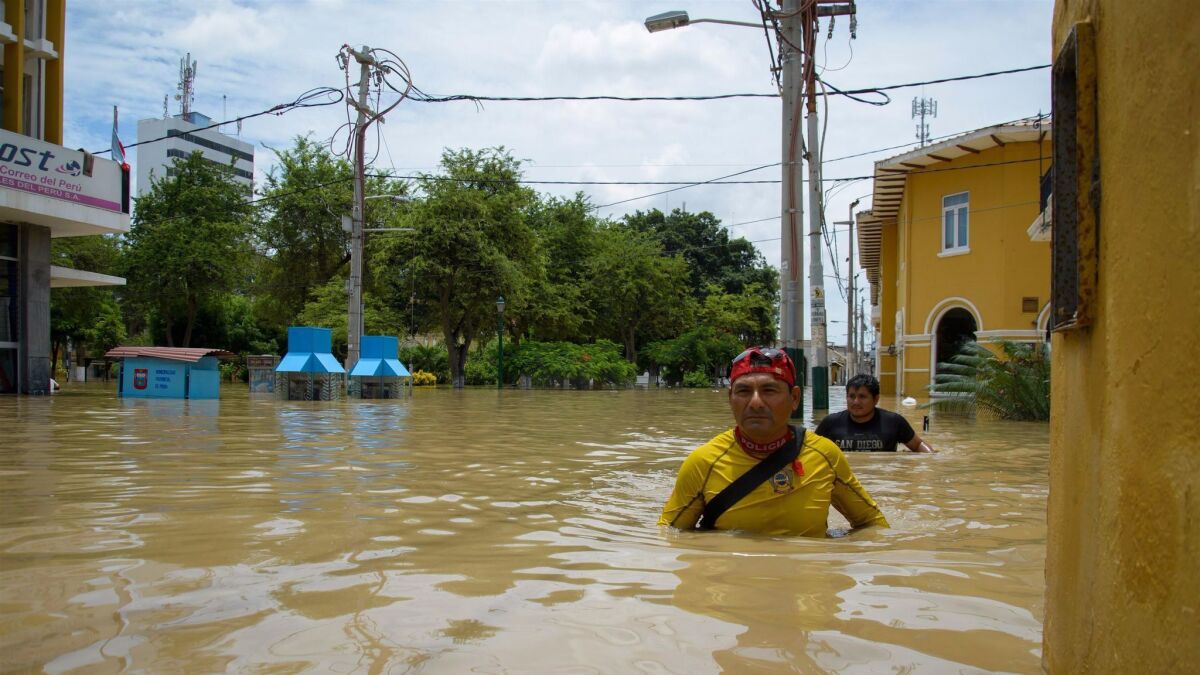 Two men make their way in Piura, where more than 1,200 people have been rescued from flooded homes.