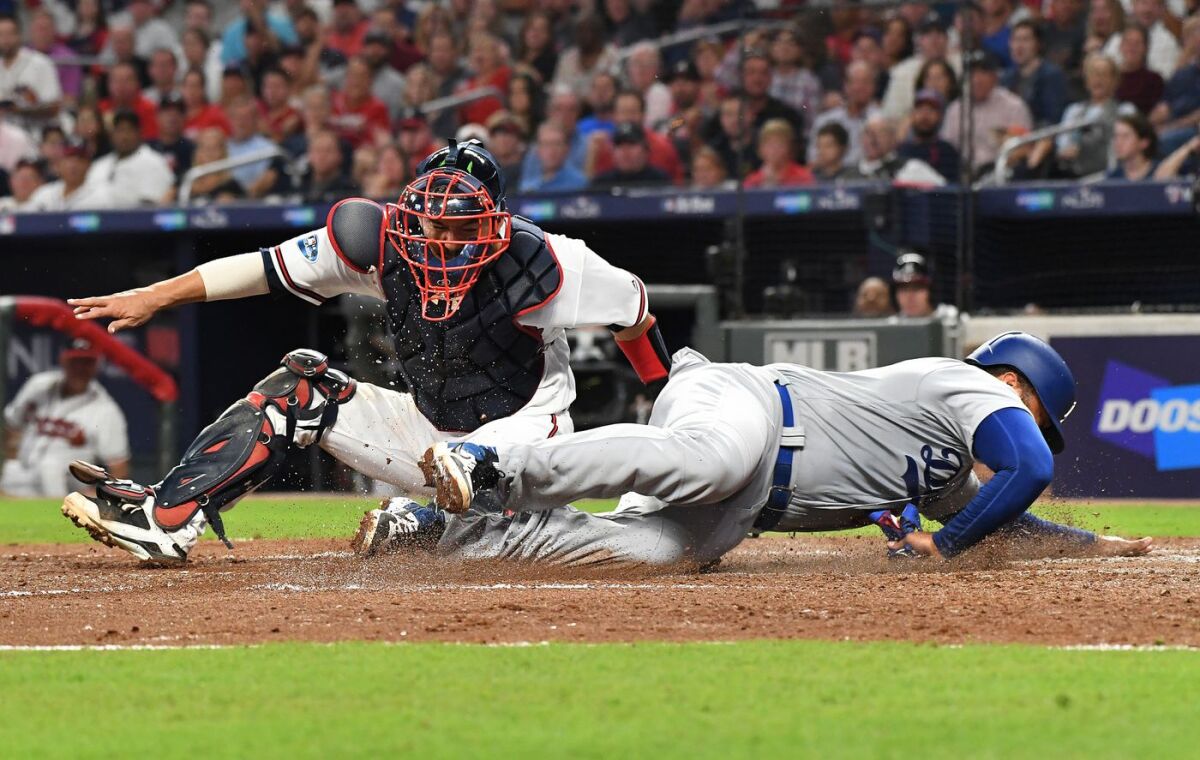 The Dodgers' Matt Kemp is tagged out by Braves catcher Kurt Suzuki in the sixth inning on Sunday.