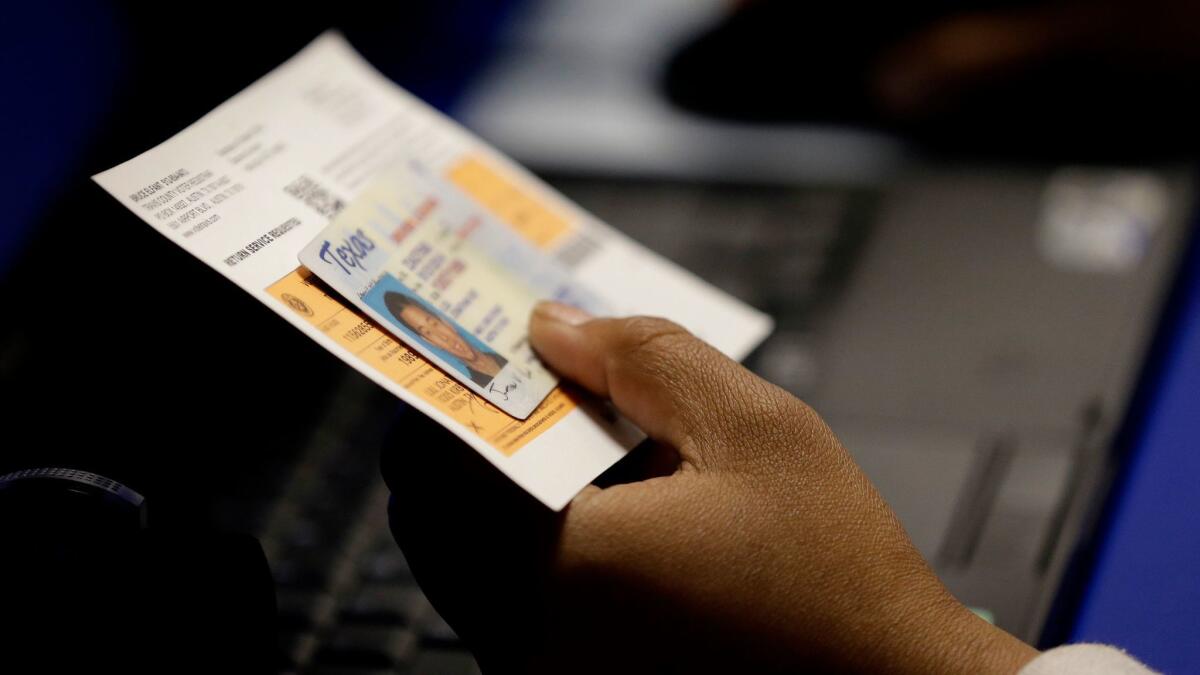 An election official checks a voter's photo identification in Austin, Texas.