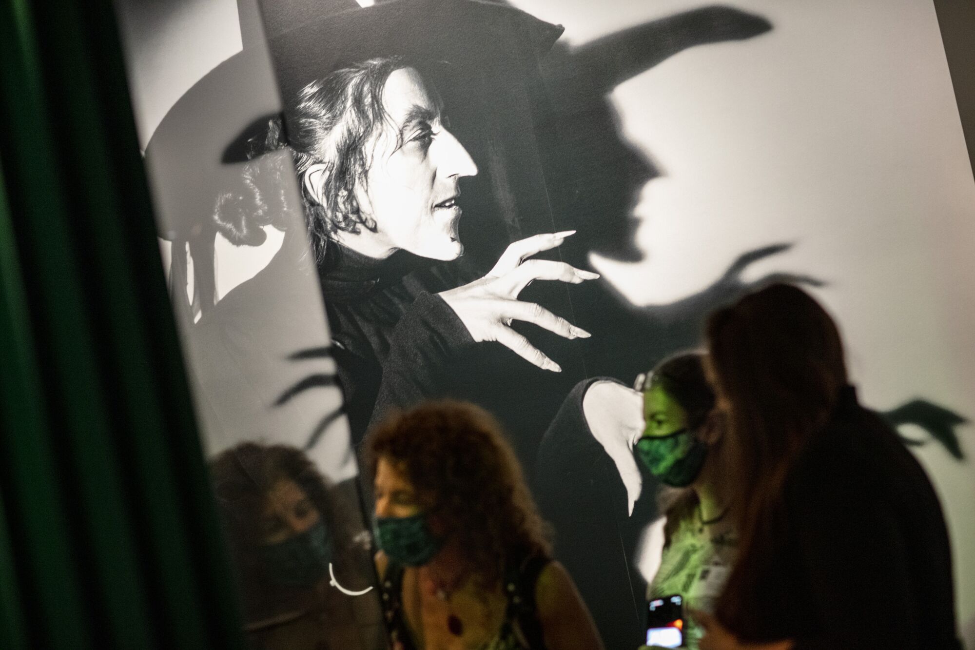 Visitors stand in front of a large photo of a witch. 