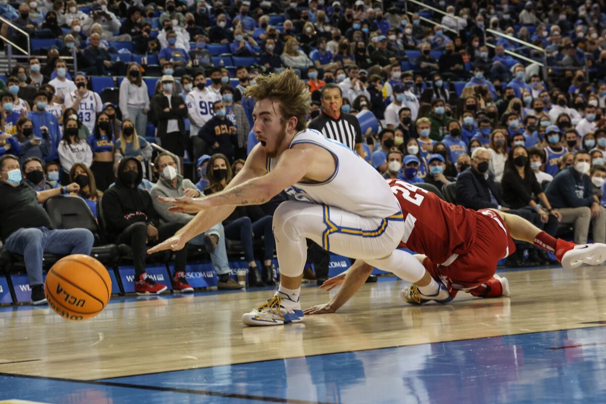 UCLA guard Jake Kyman dives for a loose ball ahead of Stanford guard Sam Beskind during the first half.