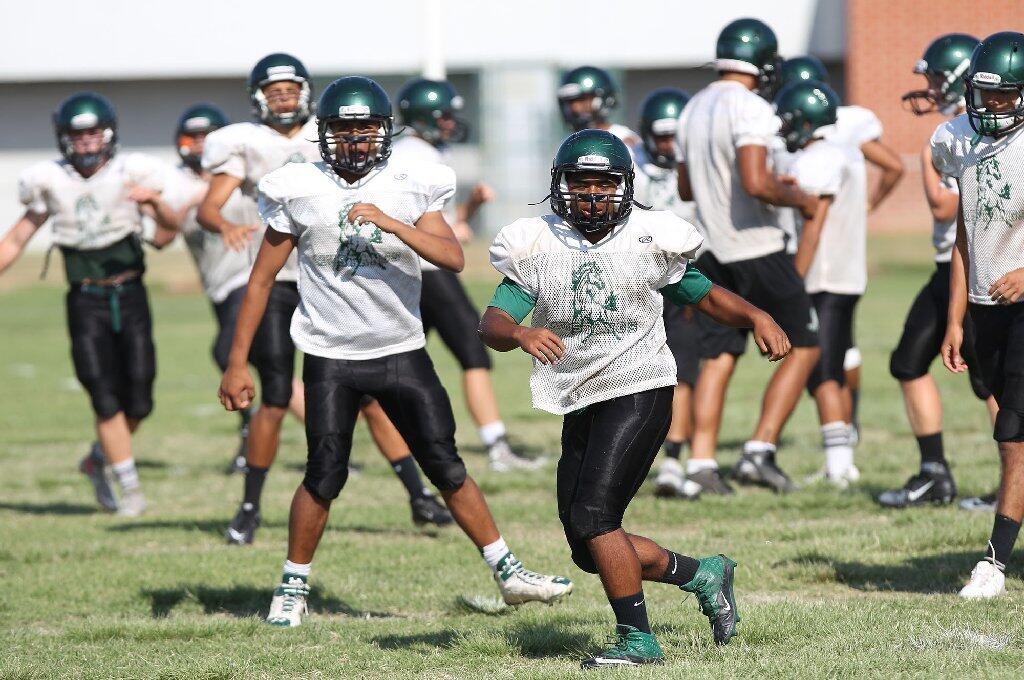 Costa Mesa High's football team goes through warm-up drills before a recent practice.