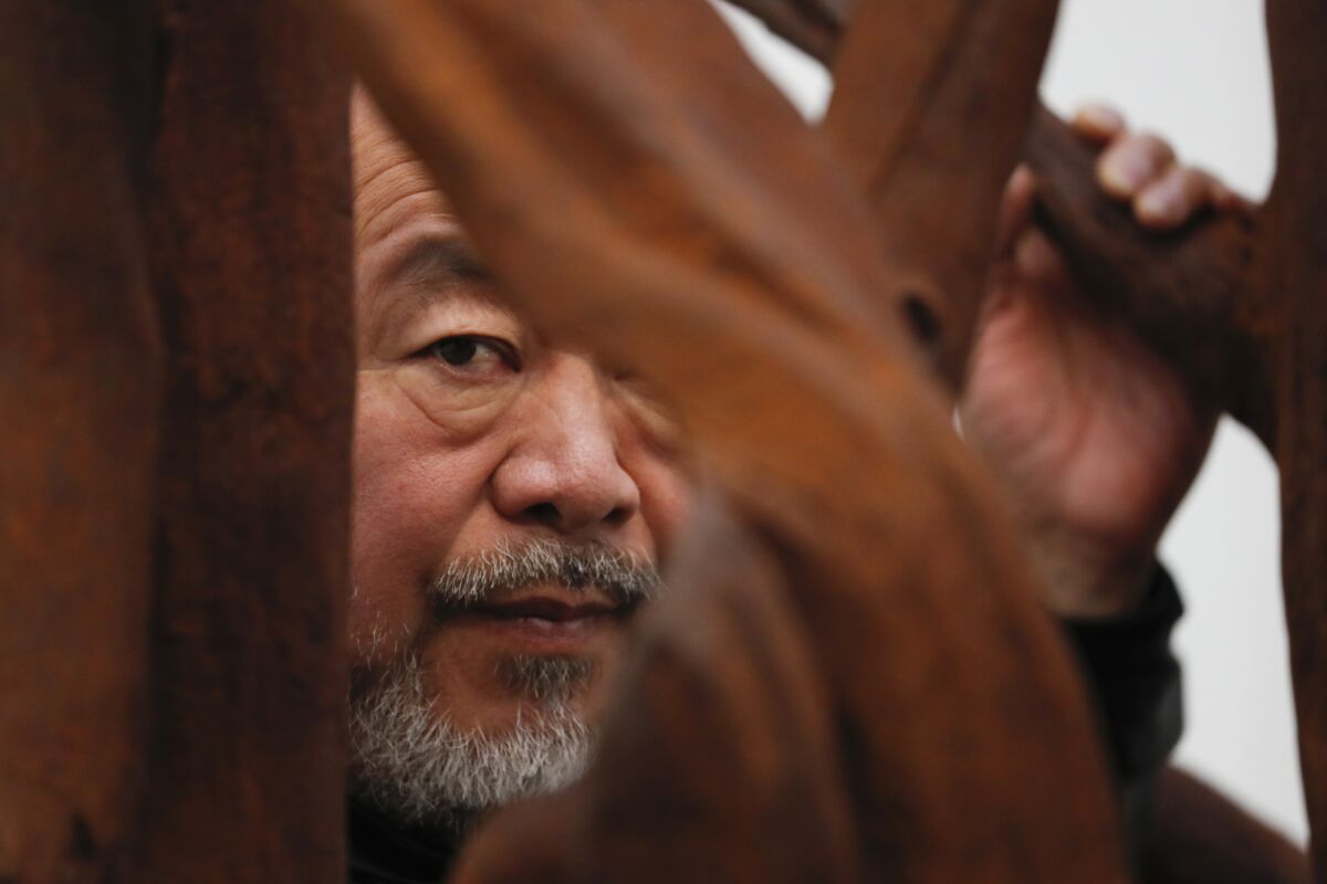 FILE - Chinese artist Ai Weiwei poses for the media with cast iron work entitled 'Martin 2019' at an art gallery in London on Oct. 1, 2019. Ai is one of China's most famous artists, and many regard him as one of the world's greatest living artists. Working with the Swiss architectural firm Herzog & de Meuron, he helped design the Bird's Nest stadium, the centerpiece of Beijing's 2008 Summer Olympics. The stadium will also host the opening ceremony for Beijing's Winter Olympics on Feb. 4, 2022. (AP Photo/Alastair Grant, File)