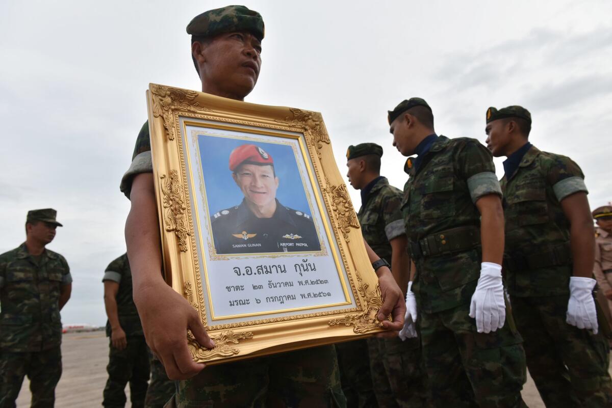 A member of the Royal Thai Navy carries a portrait of Saman Kunan, the former Thai Navy SEAL who died in the rescue mission for a soccer team trapped in a cave, during honors marking the arrival of Kunan's remains at a military base in Chon Buri province.