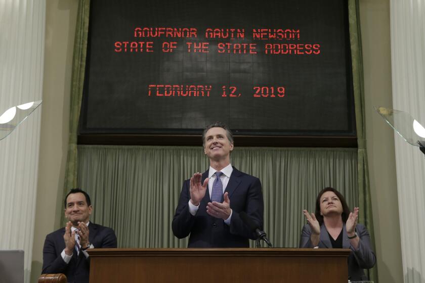 California Gov. Gavin Newsom, center, flanked by Assembly Speaker Anthony Rendon, D-Lakewood, left, and Senate President Pro Tem Toni Atkins, D-San Diego, right, applauds Camp Fire survivor Allyn Pierce during his first state of the state address to a joint session of the legislature at the Capitol Tuesday, Feb. 12, 2019, in Sacramento, Calif. Newsom praised Pierce, who survived the flames of the Camp Fire last fall and began treating patients at a hospital in Paradise when he could have fled from the Sierra Nevada foothills community. (AP Photo/Rich Pedroncelli)
