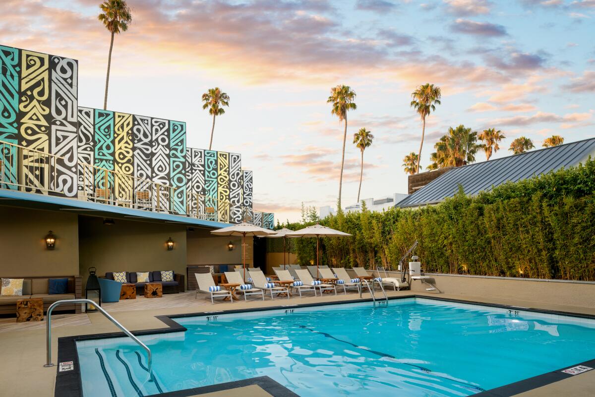 The Le Méridien Delfina pool with a colorful mural under a sunset sky