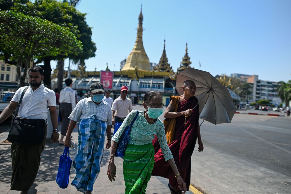 People wearing masks walk to a bus stop in Yangon, Myanmar.