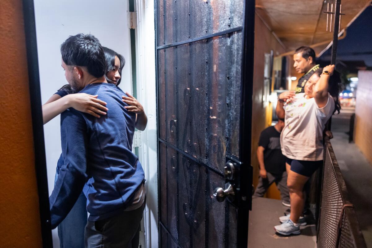 Javier Diaz, 32, left, is welcomed by his neighbors in South Los Angeles