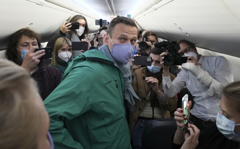 Alexei Navalny is surrounded by journalists on an airplane