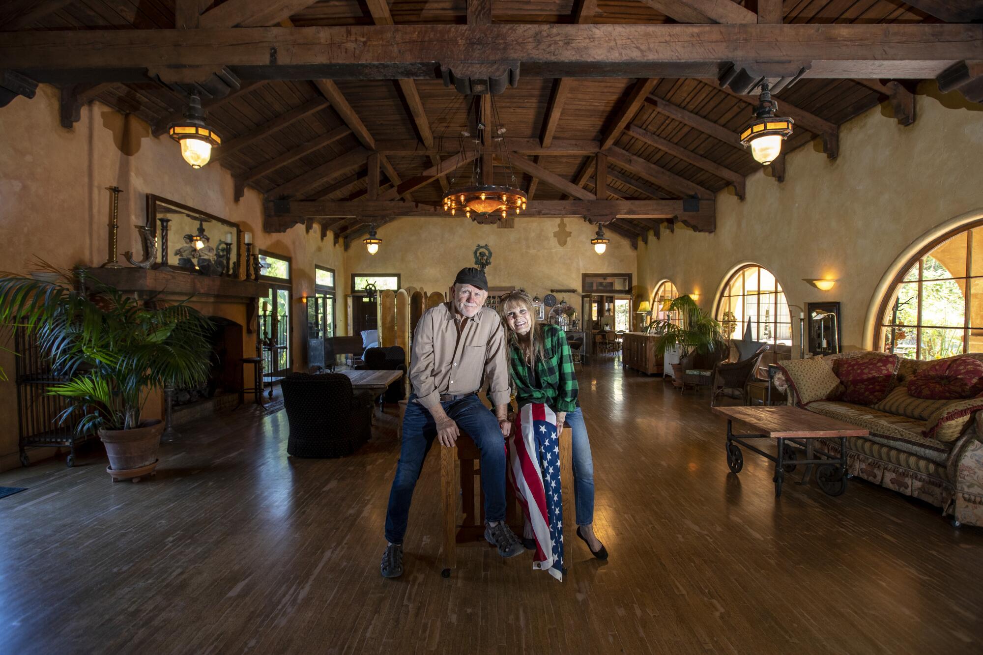 A couple in a wide-open room with wood floors and high beamed ceilings